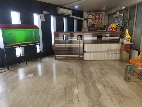Una habitación con un acuario, un refrigerador y un pequeño altar decorado con flores.