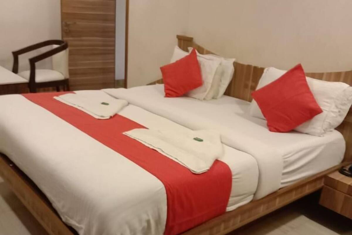 A modern bedroom with a wooden bed frame, white bedding, and red accents.