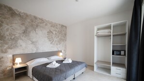 Una moderna camera d'hotel con un letto, abat-jour, un grande arazzo a parete, un armadio e una televisione a schermo piatto.