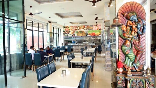 Um restaurante com mesas, cadeiras, ventiladores de teto e uma estátua decorativa.