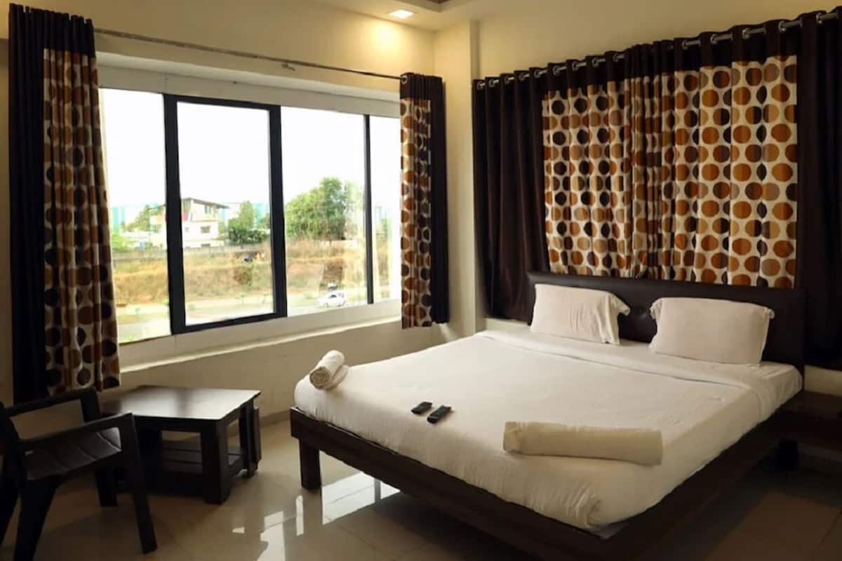 A hotel room with a large bed, a desk, and a window with curtains.