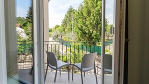 A balcony with two chairs, a glass door, and a view of trees and a fence. - Deluxe Suite 2 with Shared Pool and Private Balcony (Manerba del Garda)