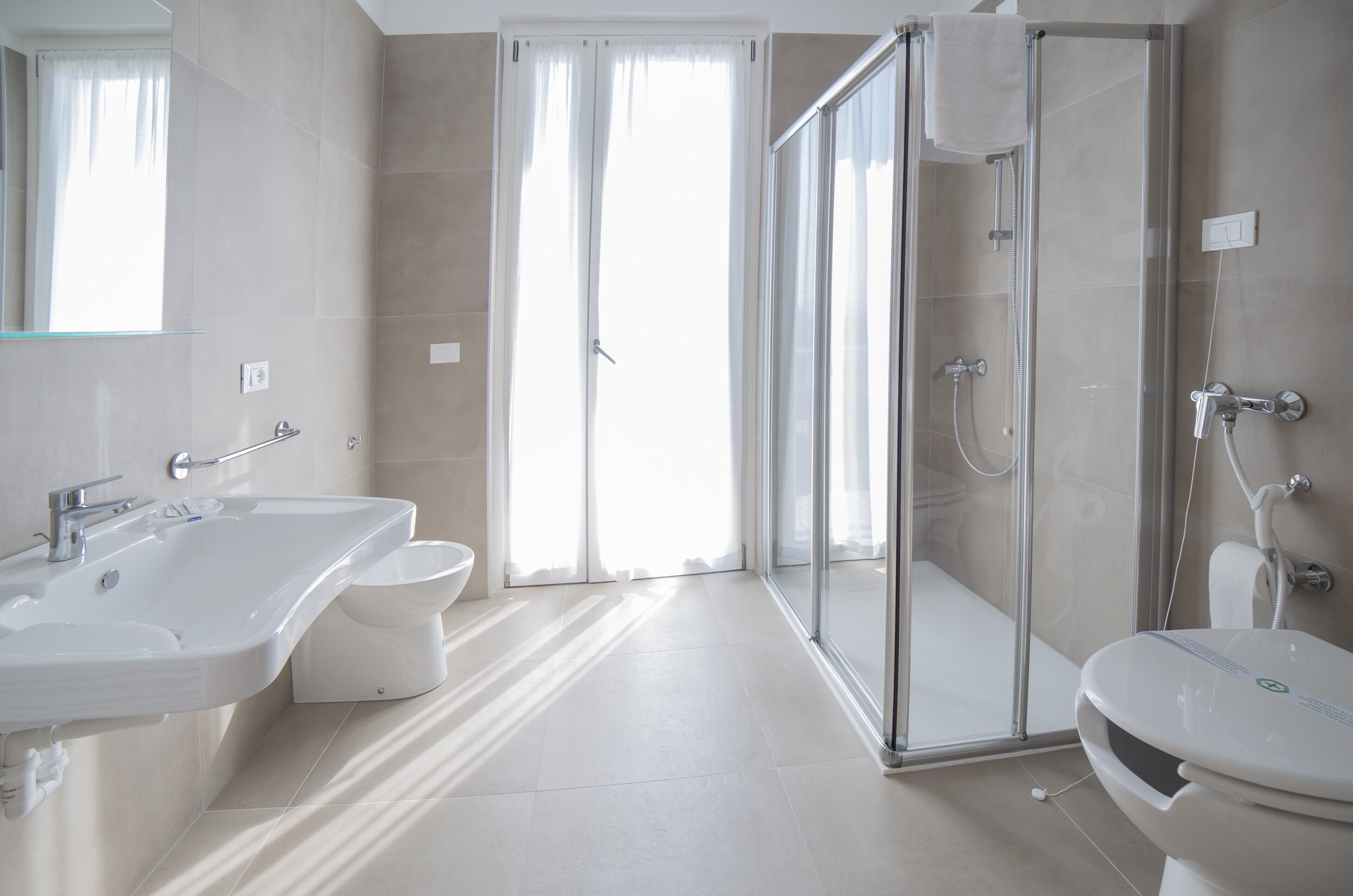 Ein modernes Badezimmer mit Duschkabine aus Glas, einem weißen Waschbecken und einer Toilette.