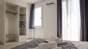 A bedroom with a bed, a wardrobe, a window, and a wall-mounted air conditioner. - Deluxe Suite 2 with Shared Pool and Private Balcony (Manerba del Garda)