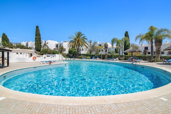Une piscine avec des chaises longues et des palmiers.
