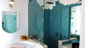 A modern bathroom with a glass shower enclosure, a white sink, and a wooden stool. - Caldera's Majesty (Santorini)