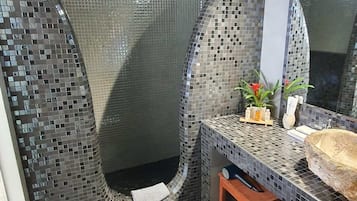 Bathroom features a unique design with mosaic tile walls and a natural stone sink.