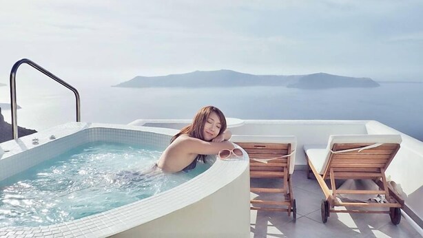 A person relaxing in a hot tub with a view of islands in the distance. - Caldera's Majesty (Santorini)
