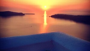 A sunset view from a balcony with a planter of rocks and plants. - Caldera's Majesty (Santorini)