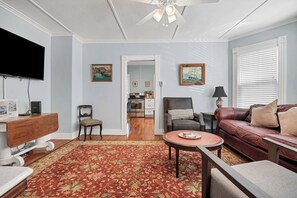 A living room with a television, a fireplace, a sofa, a coffee table, and a patterned rug.