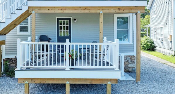 A covered porch with a white railing, a door, and a small window.