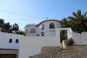 Um edifício branco com parede de pedra e portão.