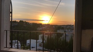 Een balkon met uitzicht op een zonsondergang boven een woonwijk.