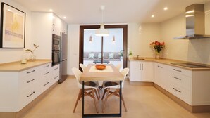 A modern kitchen with white cabinetry, a dining table, and a pendant light. - 1130 Casa Antana (Frigiliana)