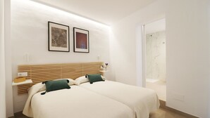 A hotel room with two beds, a wooden headboard, a small bedside table, and a framed picture on the wall. - 1130 Casa Antana (Frigiliana)