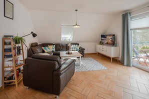 Una sala moderna con un sofá de cuero, una mesa de centro, una estantería y un televisor.