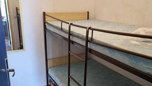 A bunk bed with a wooden headboard and a mattress with a floral pattern. - Ground-Floor Studio Cabin for 4 with Terrace – 300m from Beach & Shops (Argelès-sur-Mer)
