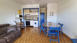A compact living space with a kitchenette, a dining area, and a sofa. - Ground-Floor Studio Cabin for 4 with Terrace – 300m from Beach & Shops (Argelès-sur-Mer)