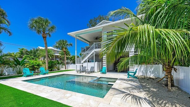 A two-story house with a covered patio and a swimming pool. - Aloha Fern: North End Beach House, Pool by Anna Maria Life Vacation Rentals (Anna Maria)