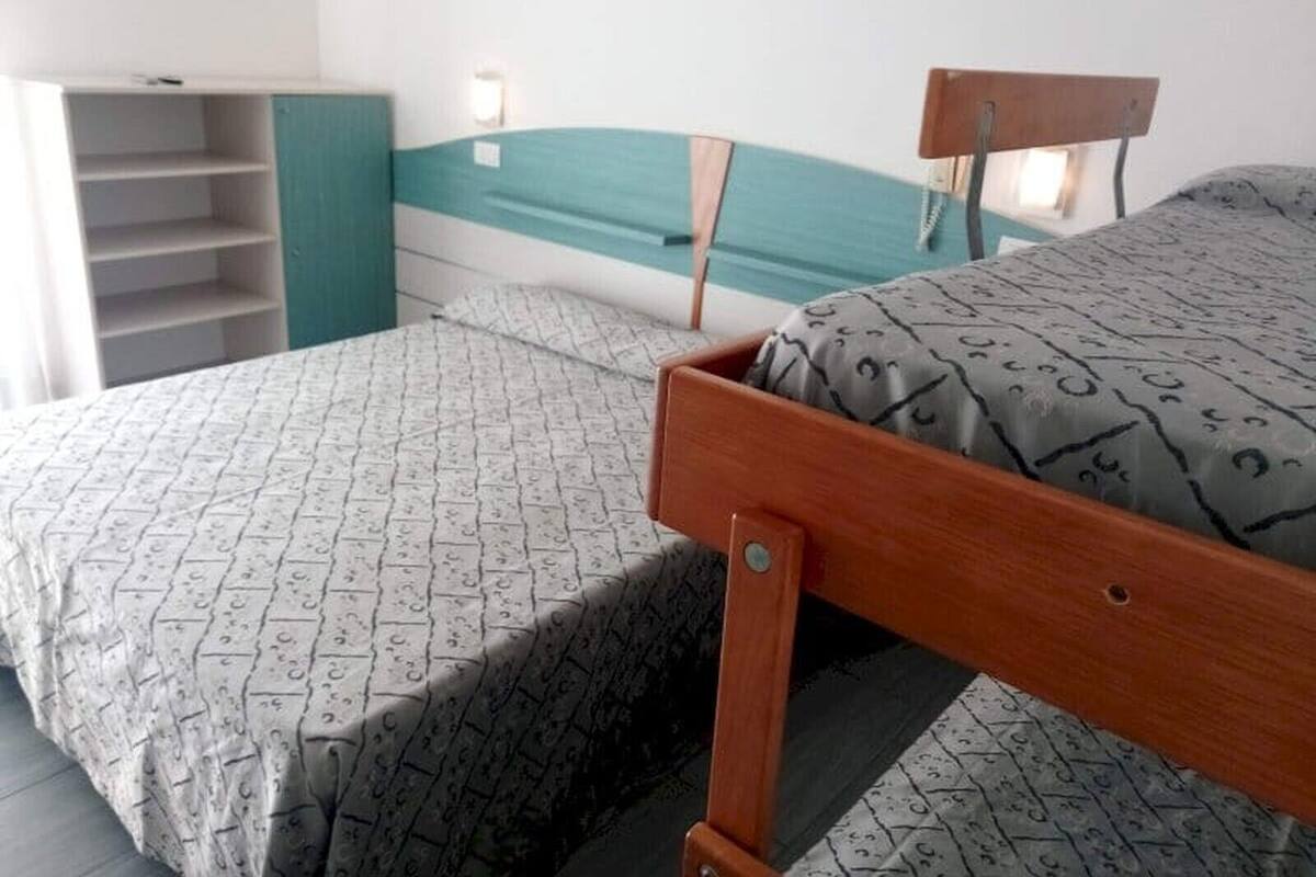 Een kamer met een bed, een houten hoofdeinde, een nachtkastje en een ingebouwde boekenkast.