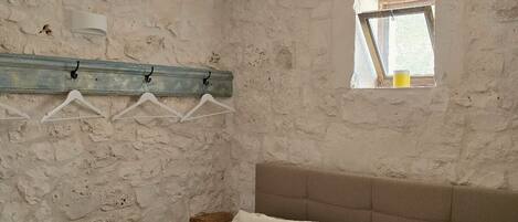 Une chambre rustique comprenant un lit, des serviettes, une petite fenêtre et un porte-serviettes fixé au mur.