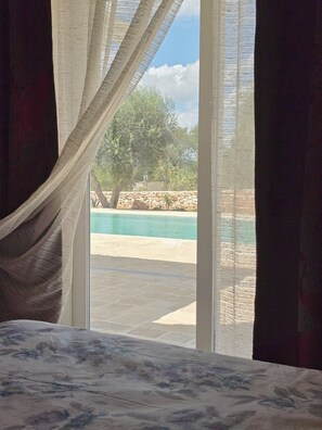 Un dormitorio con vista a una piscina y un muro de piedra.