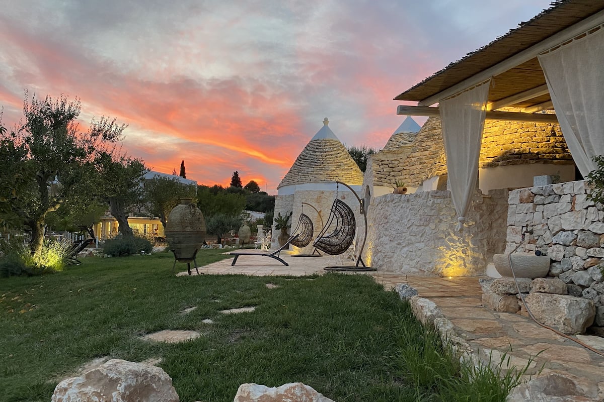 A courtyard with stone structures, a hanging chair, and a stone wall.
