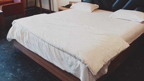 Ett hotellrum med en stor säng, ett skrivbord, en stol och en spegel.