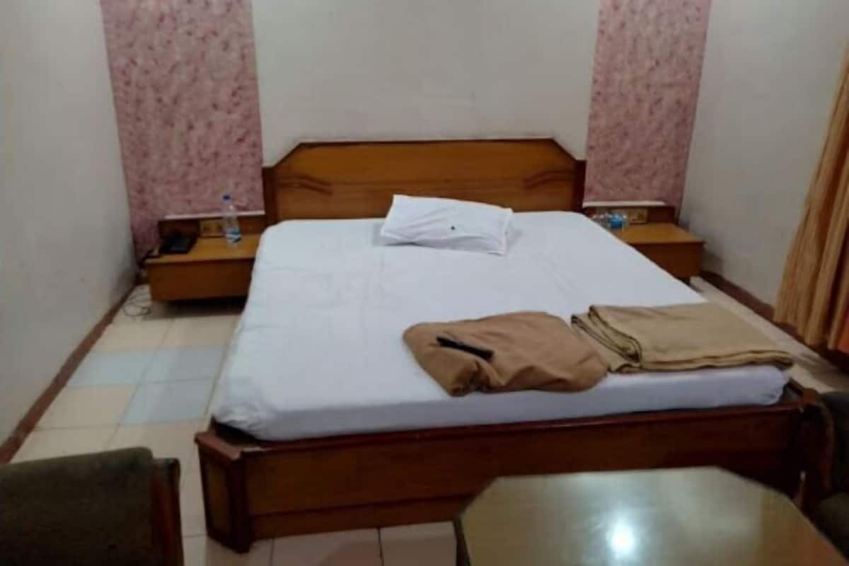 Un dormitorio pequeño y ordenado con una cama individual, una mesita de noche, una silla y una pequeña mesa.