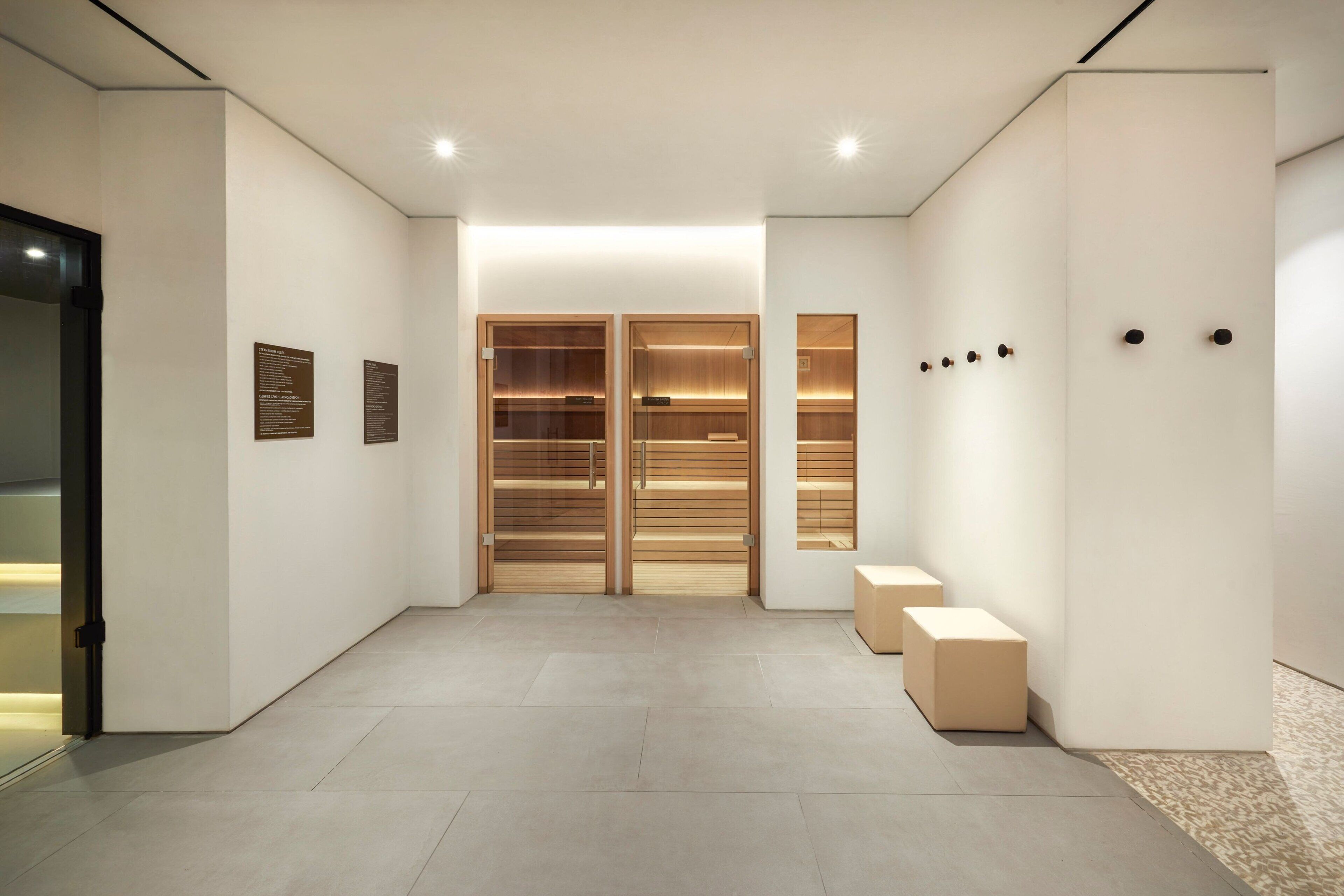 A modern hallway with a glass door, wooden shelving units, and a bench.