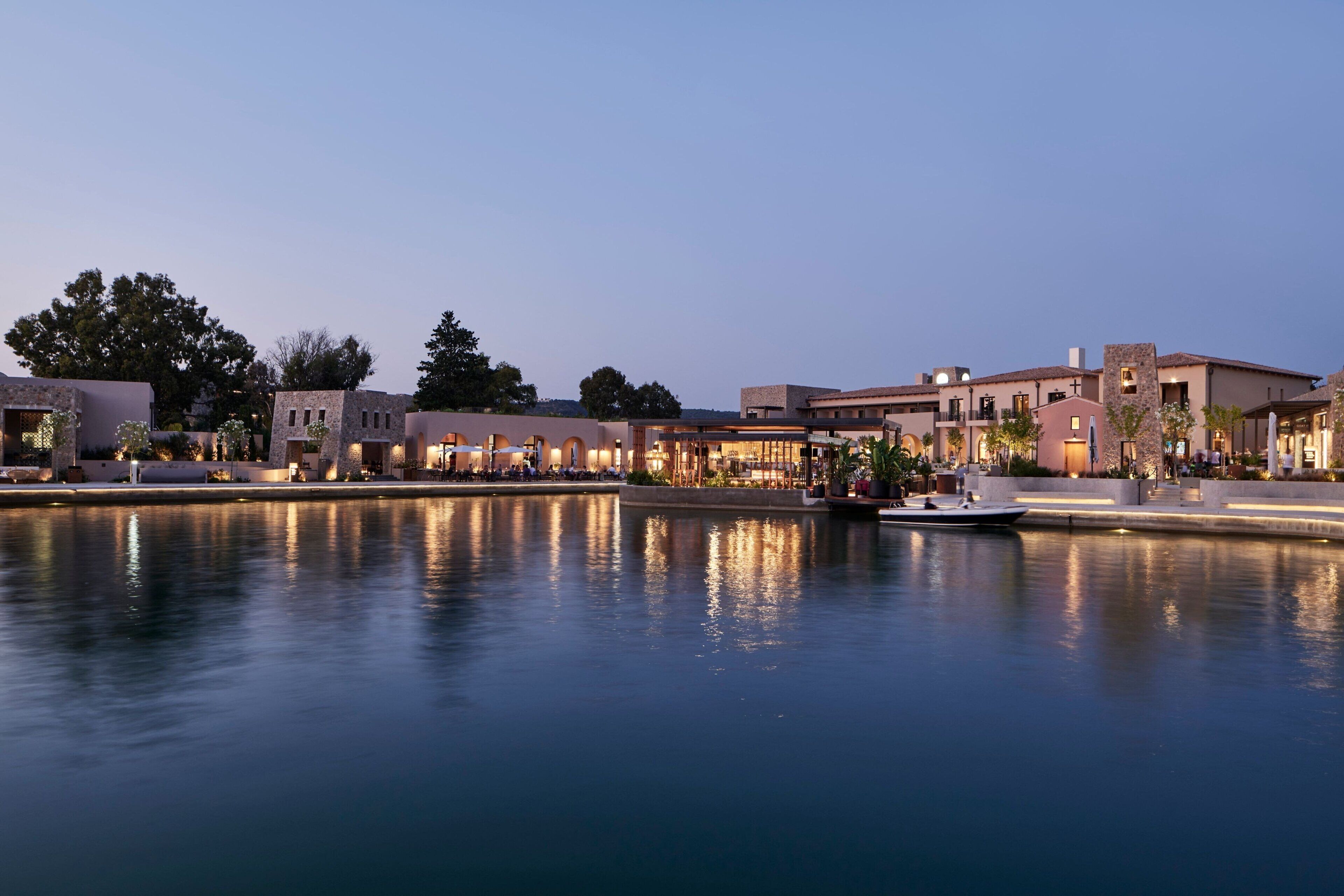 A waterfront hotel with a calm water body reflecting the buildings.