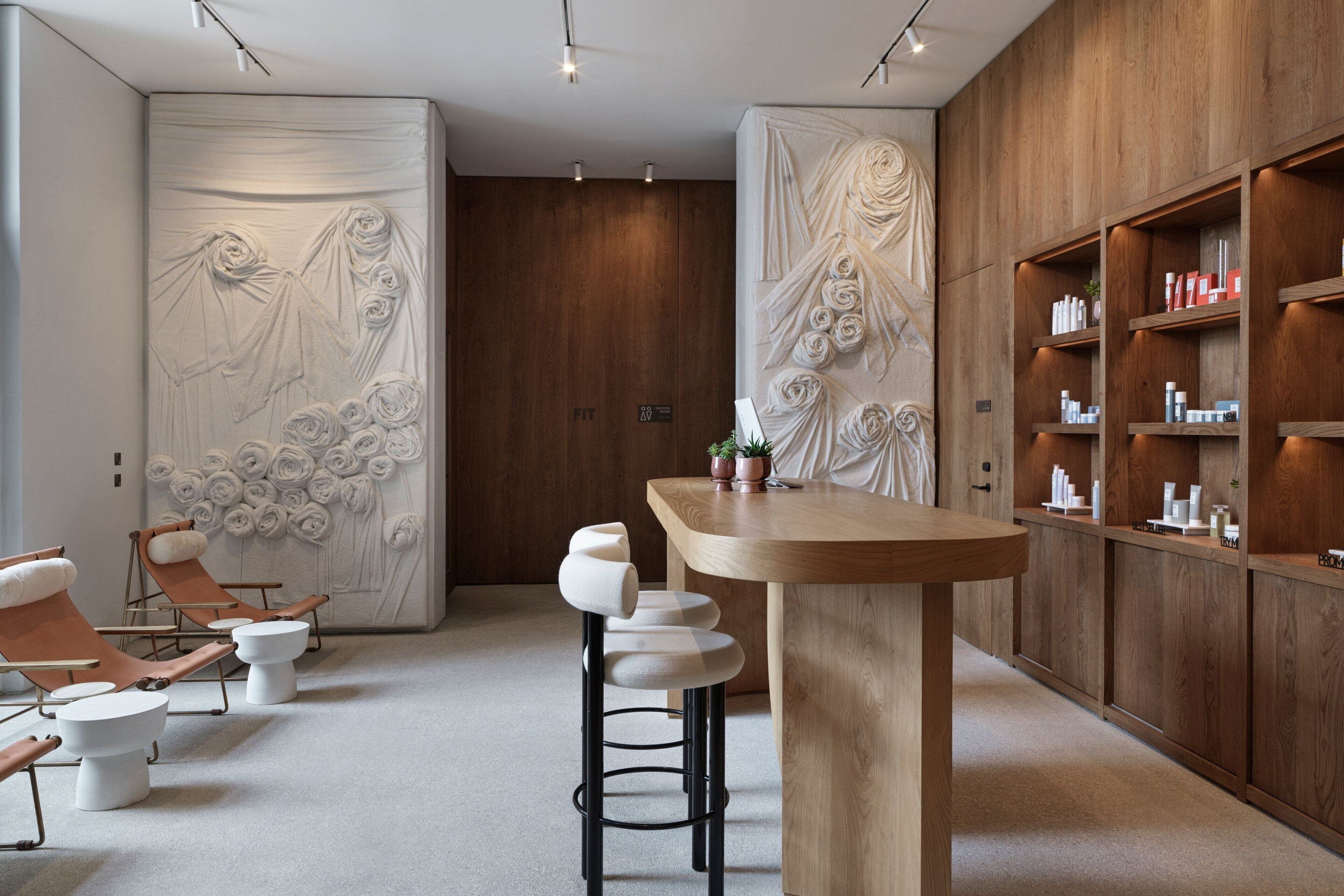 Ein moderner Spa-Bereich mit einem Holzbüro, einer Bar und einer Sitzecke mit gepolsterten Stühlen.