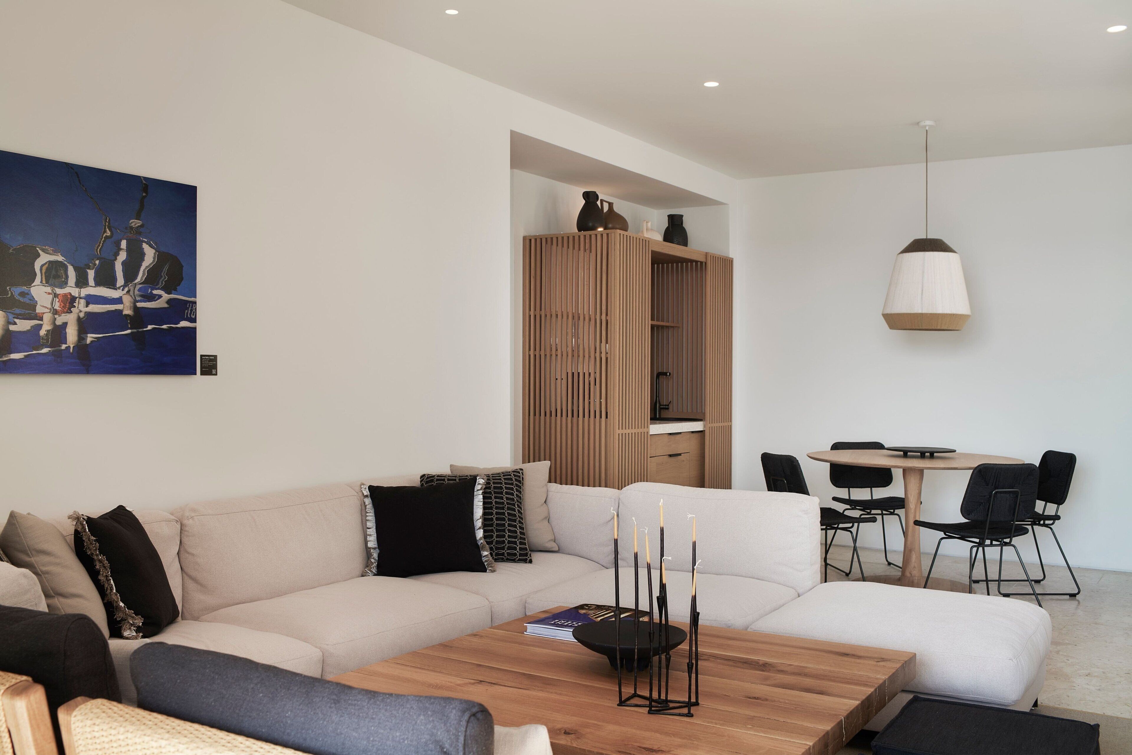 A modern living room with a sofa, coffee table, and a dining area with chairs and a table.