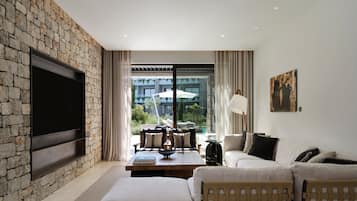 A modern living room with a stone wall, a flat-screen TV, a sofa, and a view of the outdoors.