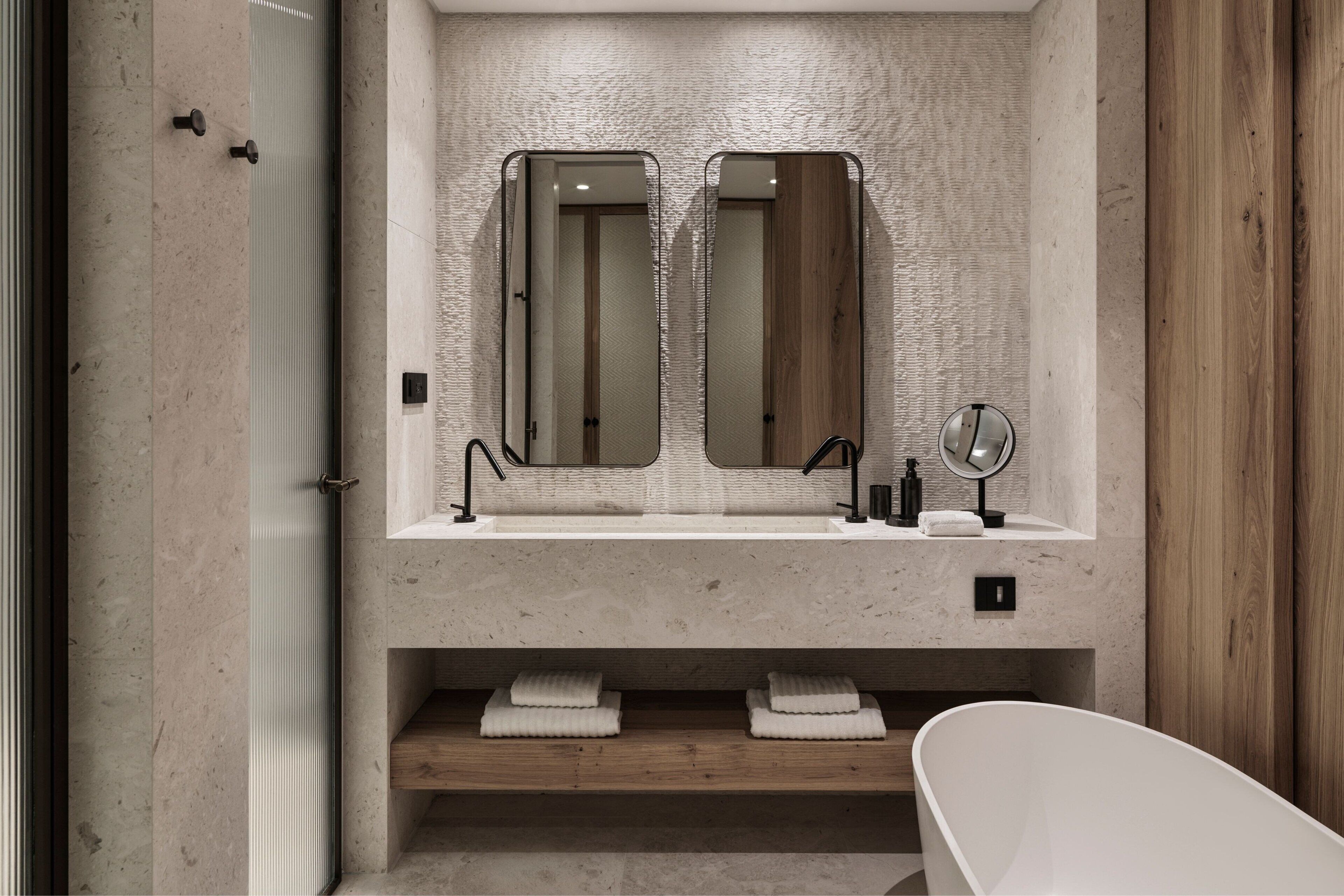 Ein modernes Badezimmer mit einem Doppelwaschbecken, zwei Spiegeln, einem Waschtisch und einer freistehenden Badewanne.