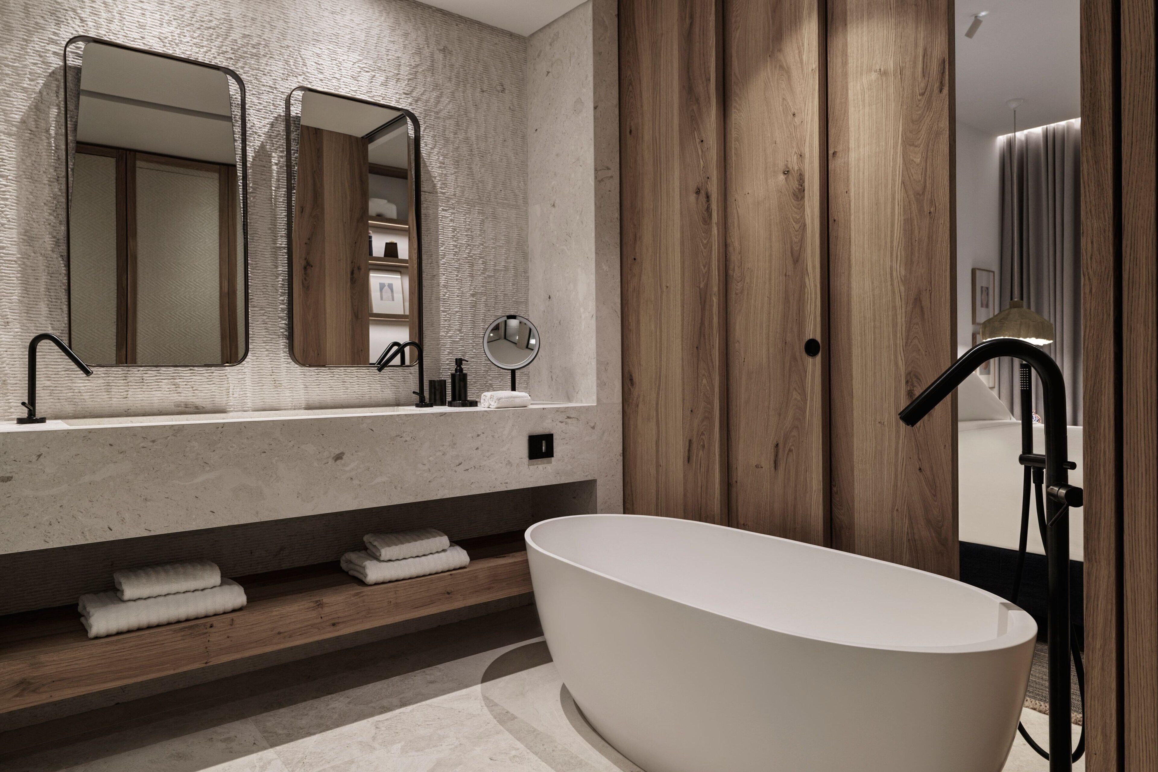 Ein modernes Badezimmer mit freistehender Badewanne, Holzverkleidung und einem großen Spiegel über dem Waschbecken.