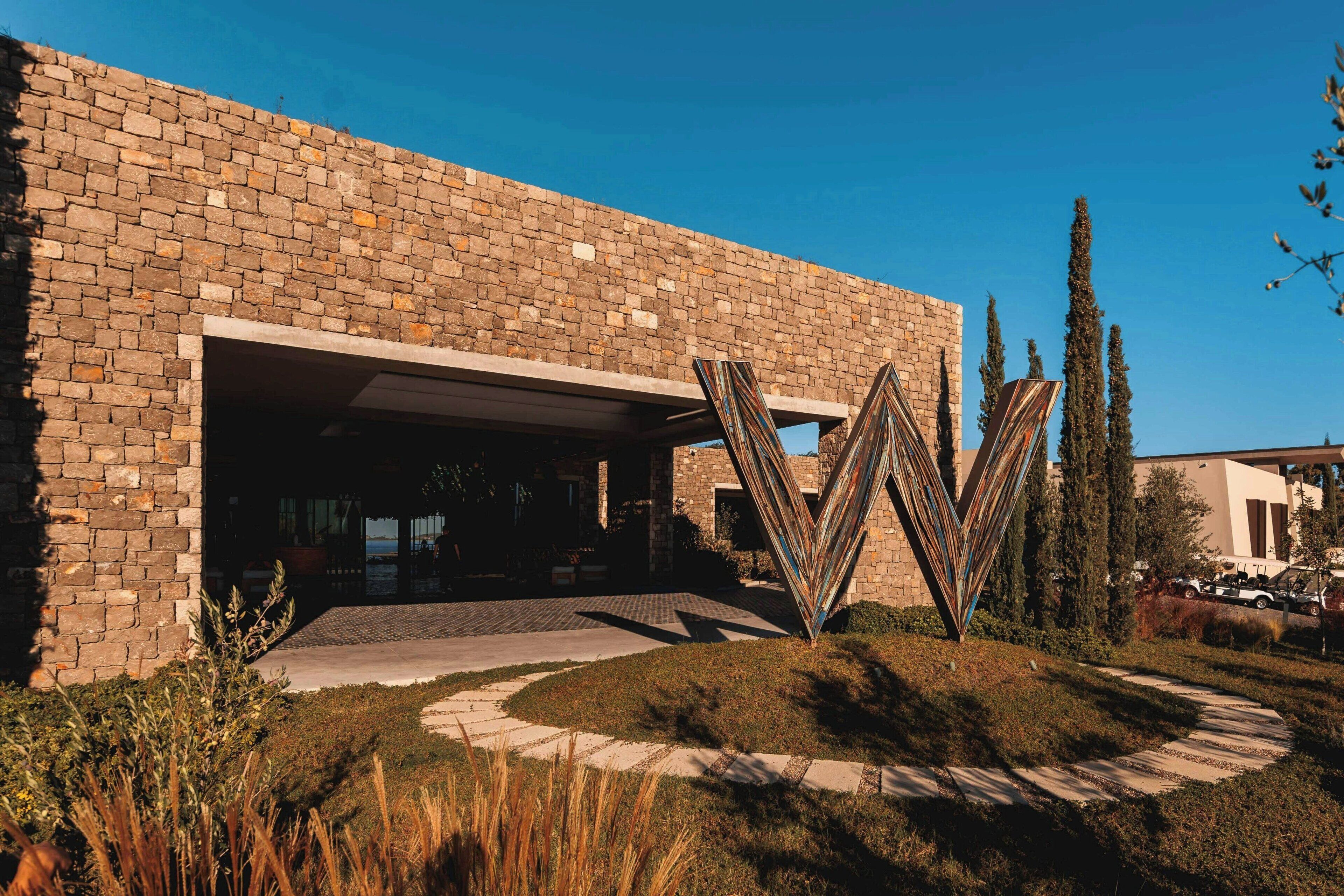 Un edificio moderno con fachada de ladrillo, una entrada amplia y una escultura metálica distintiva.