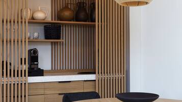 A modern kitchen with wooden cabinetry, a countertop, and a dining area with a round table and black chairs.