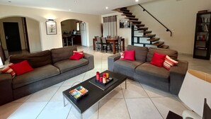 Ein geräumiges Wohnzimmer mit zwei Sofas, einem Couchtisch und einer Treppe zu einer oberen Ebene.