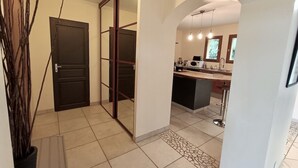 Eine moderne Küche mit einer zentralen Kochinsel, einem Essbereich mit Bar und einer sichtbaren Tür zu einem weiteren Raum.