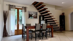 Ein Essbereich mit Holztisch und -stühlen, eine Treppe mit Holzstufen und eine Tür, die nach draußen führt.