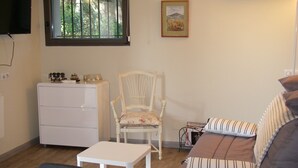 Un espacio habitable compacto con un aparador blanco, una silla blanca, una mesita pequeña blanca y un sofá con almohadas a rayas.