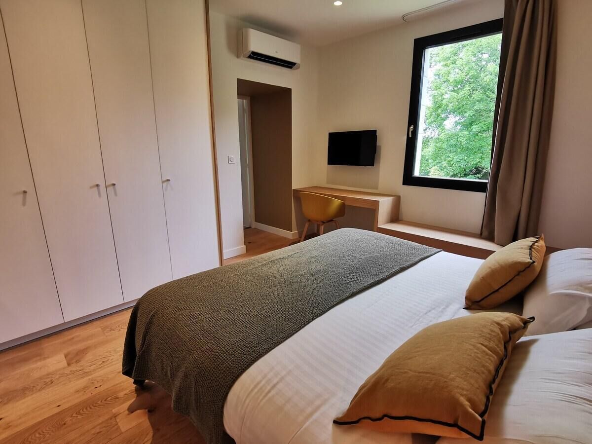 Ein Schlafzimmer mit einem Bett, Kissen, einem Schreibtisch und einem Fernseher.