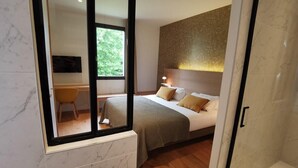 A modern bedroom with a large bed, a bedside table, a chair, and a window. - Le Corentin        . (Concarneau)