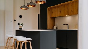 Eine moderne Küche mit Kochinsel, Holzschränken und Pendelleuchten.
