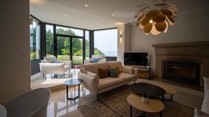 Ein modernes Wohnzimmer mit einer Couch, Sesseln, einem Fernseher und einem Kamin.