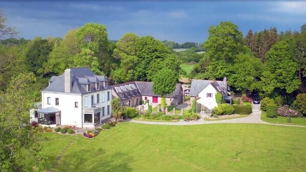 A large estate with multiple buildings, including a main house with a large garden and a smaller structure with a red door.