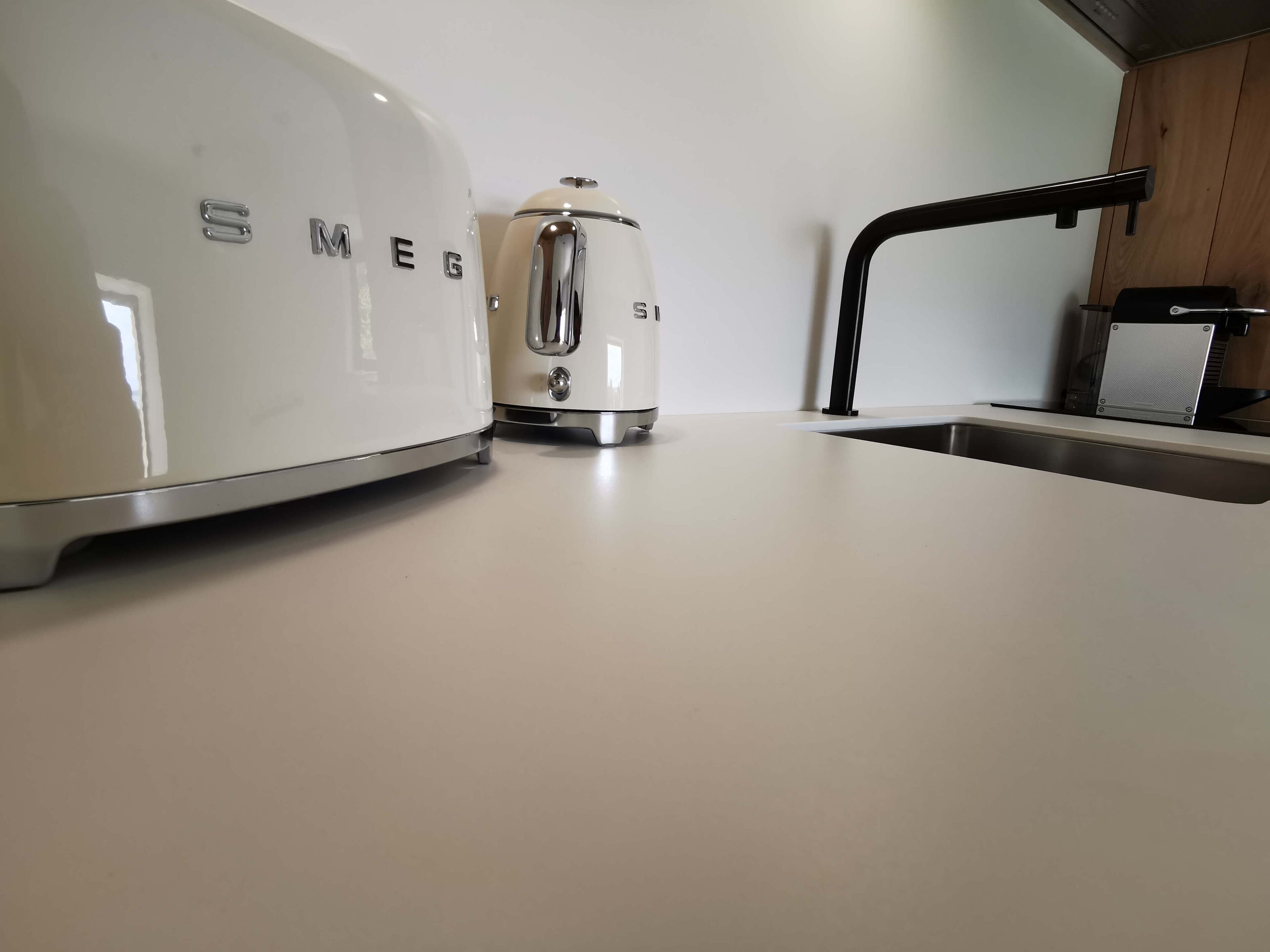 Una cocina con cubierta blanca, un hervidor eléctrico blanco y una tostadora.