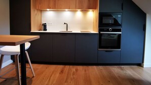 Eine moderne Küche mit dunklen Schränken, einer Holz Arbeitsplatte, einem eingebauten Ofen und einer Kaffeemaschine.