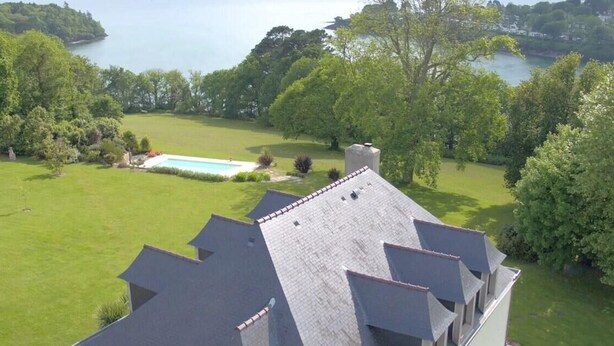 Ein Wohnhaus mit Schwimmbad, umgeben von üppiger Vegetation und Blick auf einen See.